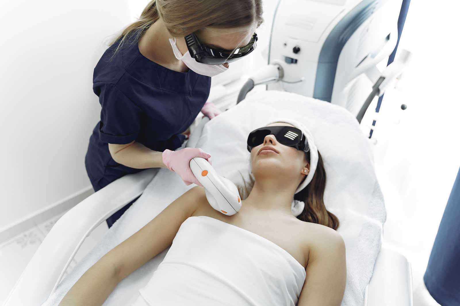 Profesional de estética, con gafas de protección, aplicando un tratamiento con aparatología en cabina.